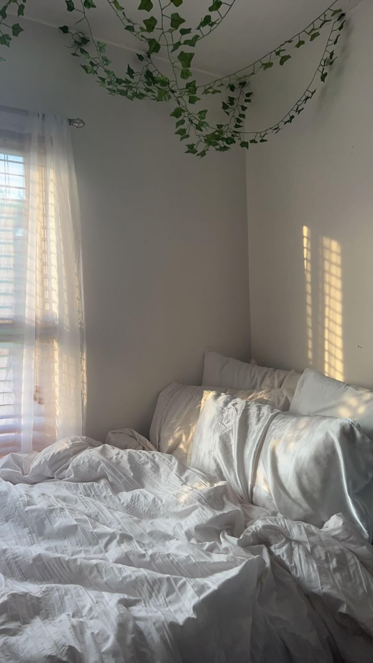 an unmade bed with white sheets and pillows in a bedroom next to a window