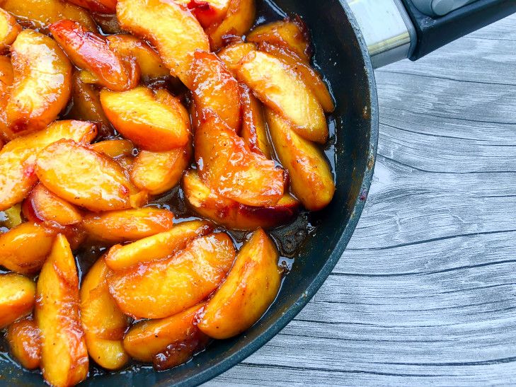 peaches are cooking in a frying pan on the table