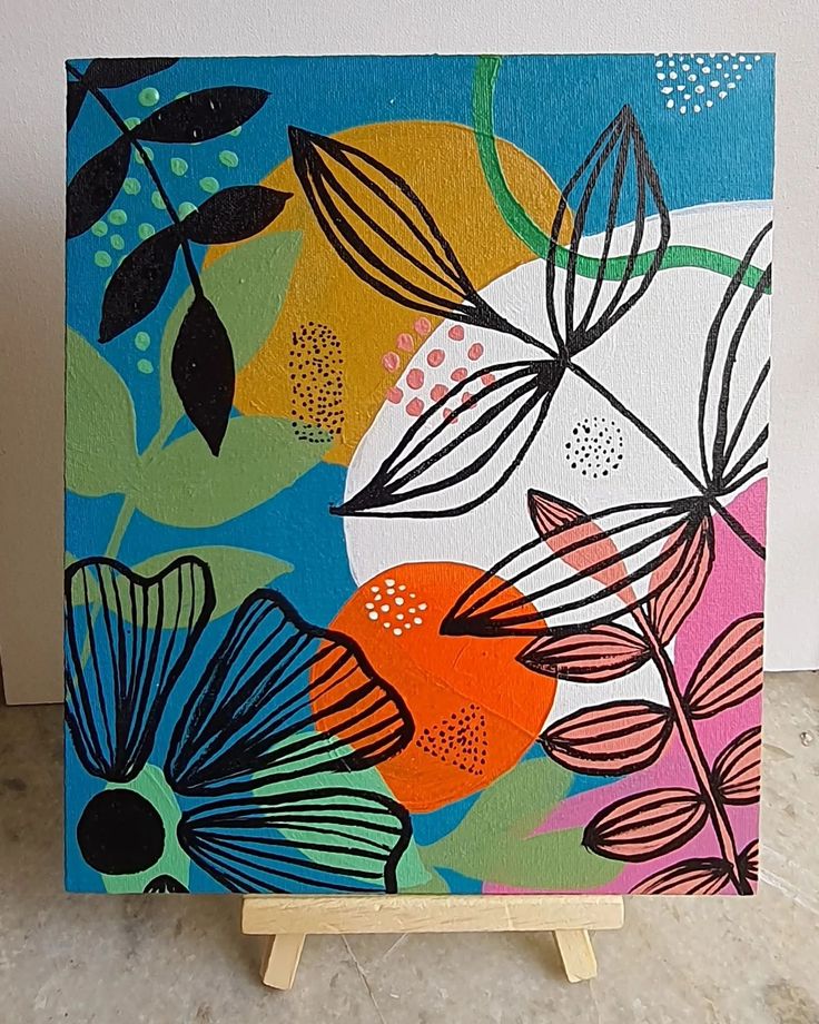 a painting on a wooden easel with flowers and leaves painted on the canvas in bright colors