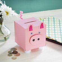 a pink piggy bank sitting on top of a table next to a vase with flowers