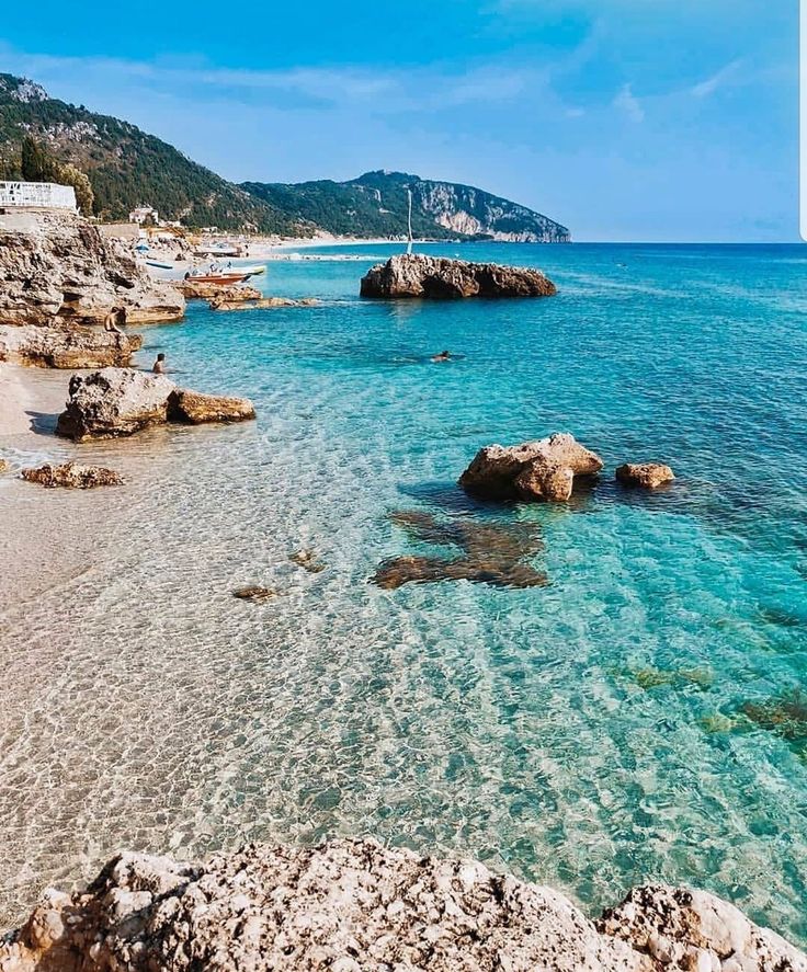 the water is crystal blue and clear with rocks on both sides in front of it