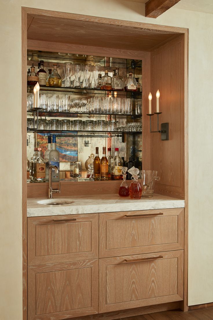 a kitchen with wooden cabinets and shelves filled with liquor bottles on top of it's counter tops