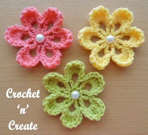 three crochet flowers with pearls on them sitting on a table next to the words, crochet n'create wohnkultutur