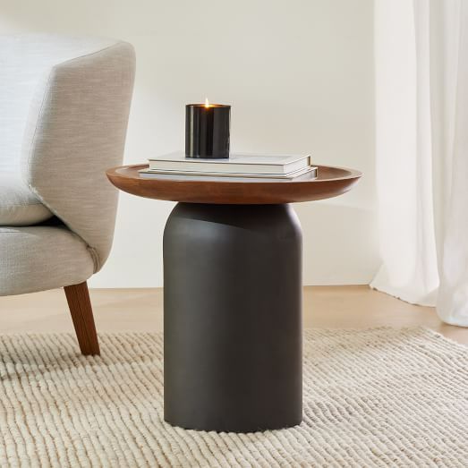 a small table with a candle on it in front of a chair and rugs