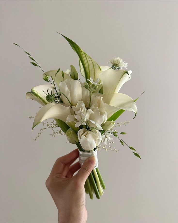 a hand holding a bouquet of white flowers