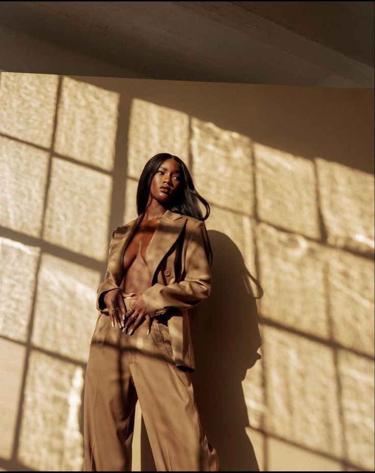 a woman standing in front of a wall with her hands on her hips and looking off to the side