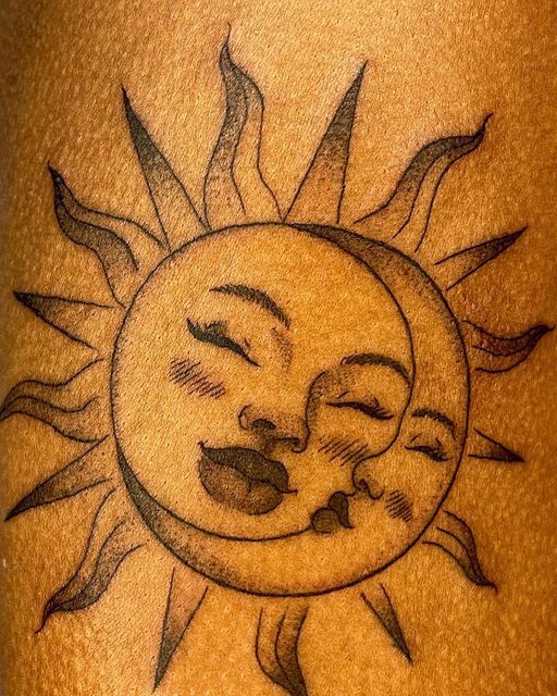 a sun and moon tattoo on the back of a man's leg, with his face painted in black ink