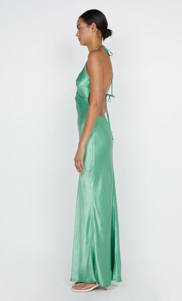 a woman in a long green dress looking back at the camera with her hand on her hip