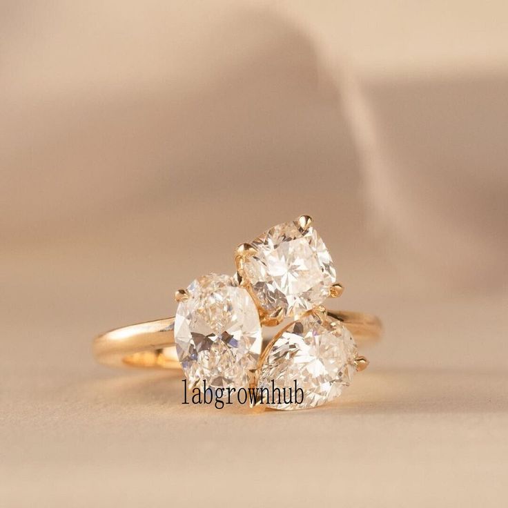 three pear shaped diamond rings on a white surface with a cloth in the back ground