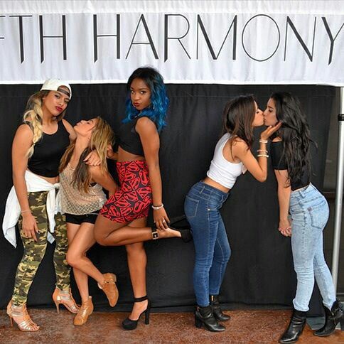 four beautiful women standing next to each other in front of a black and white sign