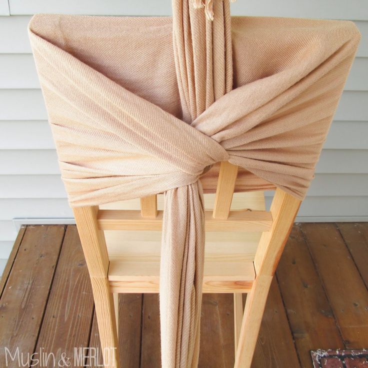 the back of a wooden chair with a beige cloth draped over it