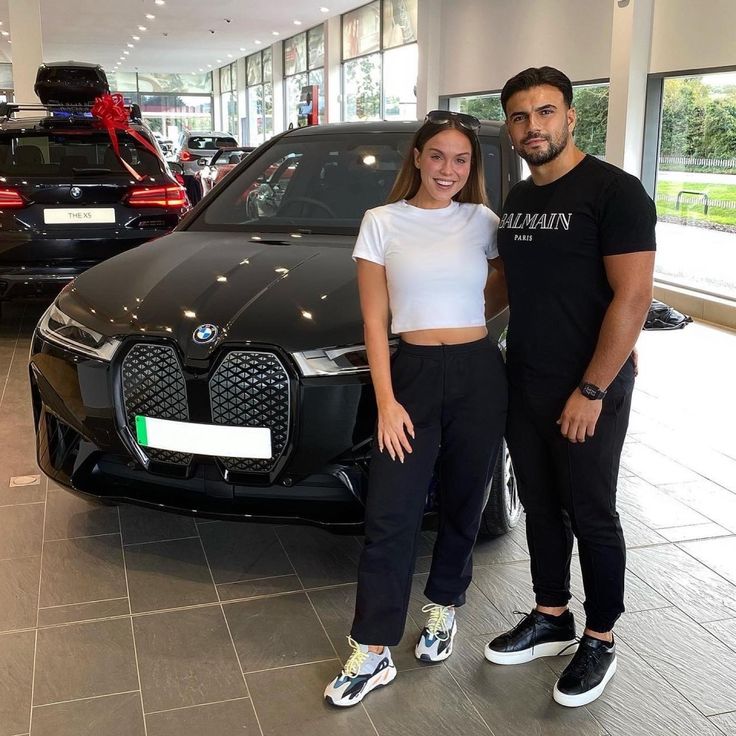 two people standing next to a car in a showroom