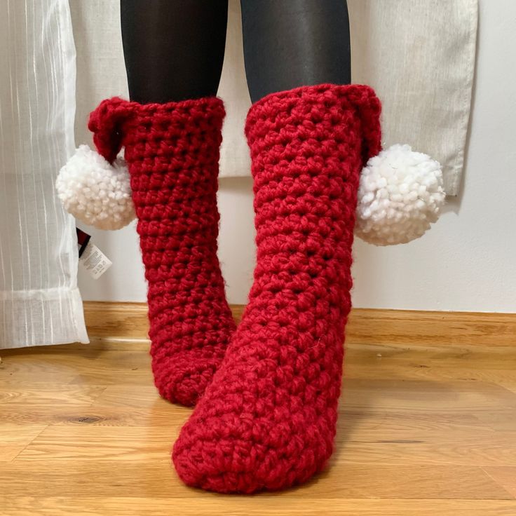 a pair of red crocheted boots with pom - poms on them