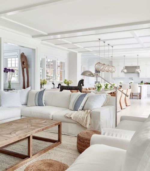 a living room filled with white furniture and lots of pillows on top of it's couches