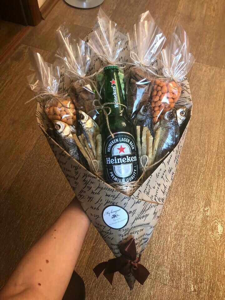 a bouquet of snacks and beer wrapped in cellophane with someone's hand