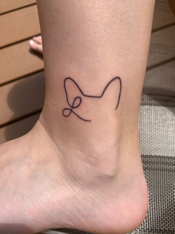 a woman's foot with a small bow tattoo on the side of her leg