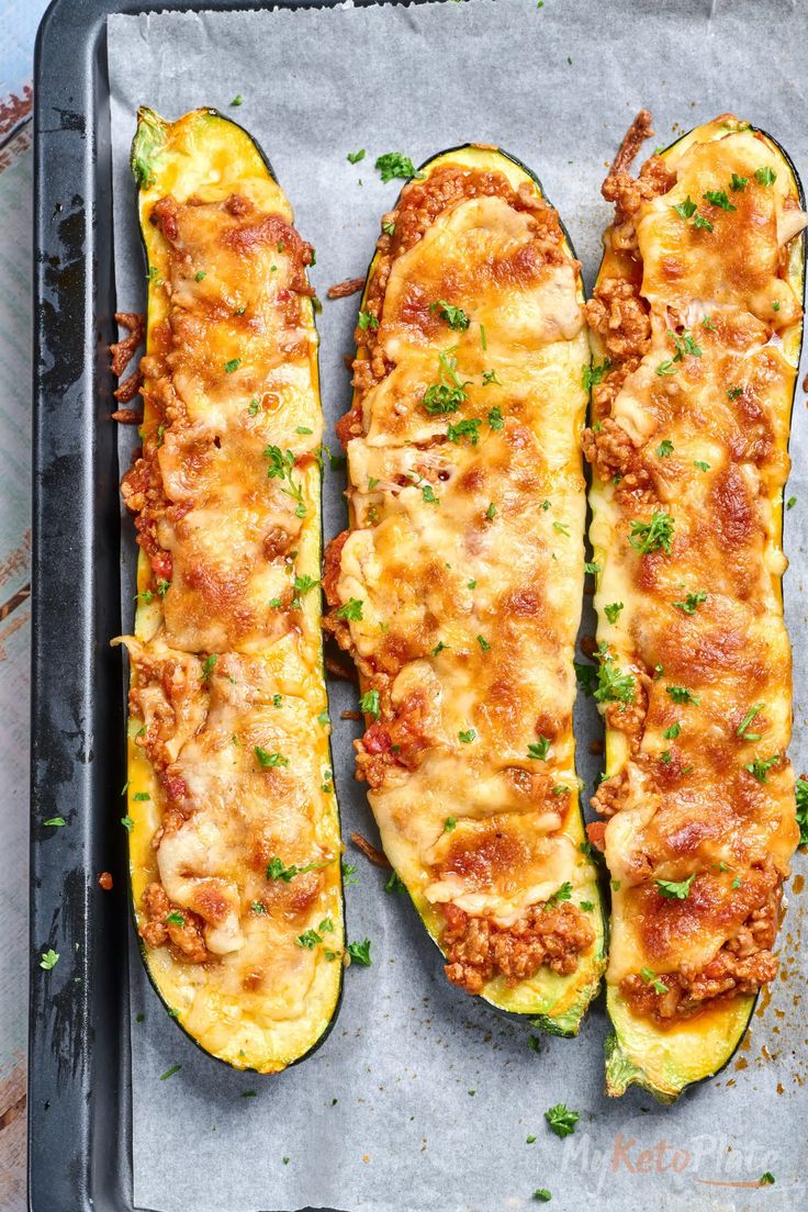 two stuffed zucchini halves on a baking sheet with cheese and parmesan