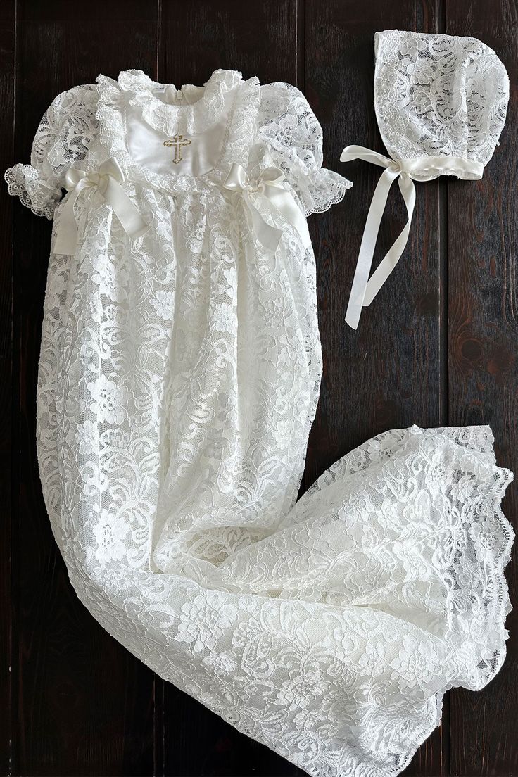 This beautiful white gown exudes elegance and tradition, making it a perfect choice for a girl's baptism ceremony. The garment is intricately crafted with delicate lace patterns, showcasing a meticulous attention to detail. The lacework, featuring floral motifs, adds a touch of vintage charm to the gown, reminiscent of timeless heirlooms passed down through generations.A standout feature is the embroidered cross on the chest, symbolizing the religious significance of the baptismal rite. The gown Silver Flower Girl Dress, Toddler Girl Christmas Dresses, Lace Baby Bonnet, Girls Gold Dress, Purple Flower Girl Dress, Flower Girl Dresses Blue, Toddler Christmas Dress, Lace Bonnet, Pink Flower Girl Dresses