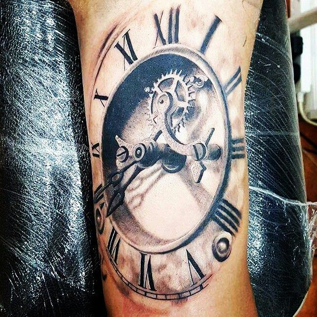 a black and white clock tattoo on the arm