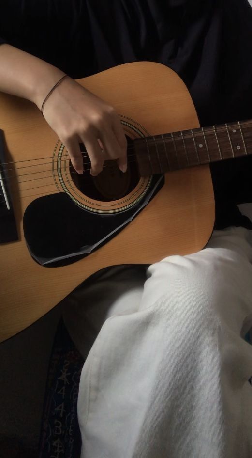 a person sitting down playing an acoustic guitar