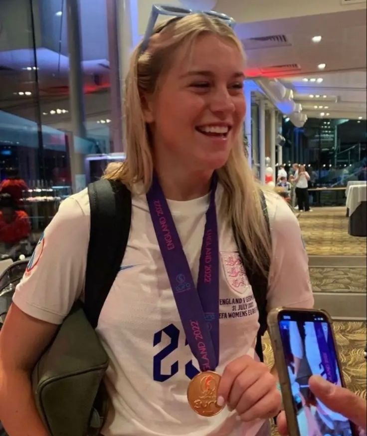 a woman holding a cell phone and wearing a medal