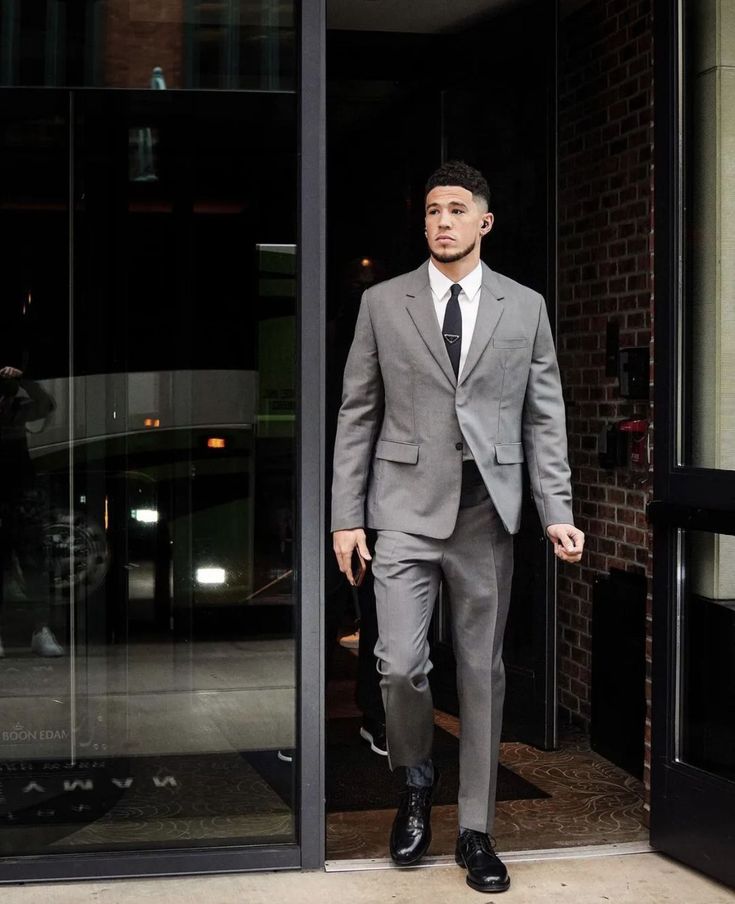 a man in a suit and tie walking out of a building with his hands in his pockets