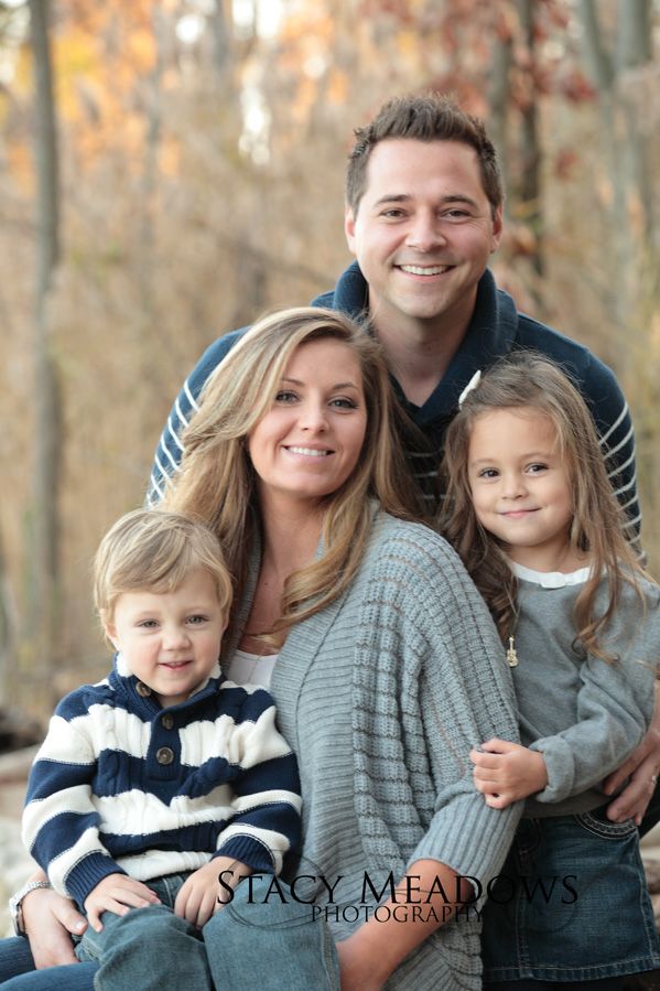 a man, woman and two children posing for a photo in front of some trees