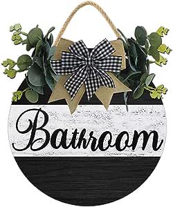 a black and white sign with a bow hanging from it's side, that says bathroom