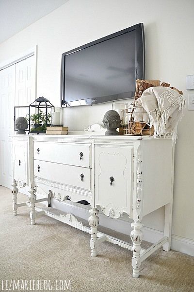 a white dresser sitting in front of a flat screen tv