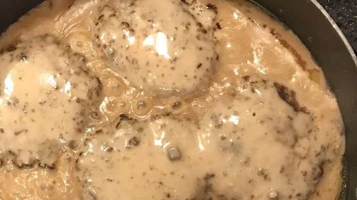 a skillet filled with cheese and meat covered in gravy on top of a stove