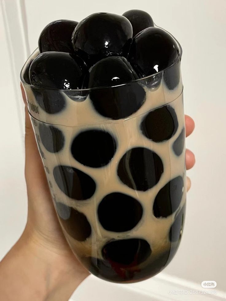 a hand holding a black and white glass with polka dots