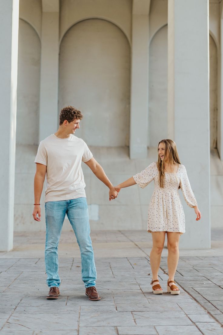 a man and woman holding hands in front of pillars