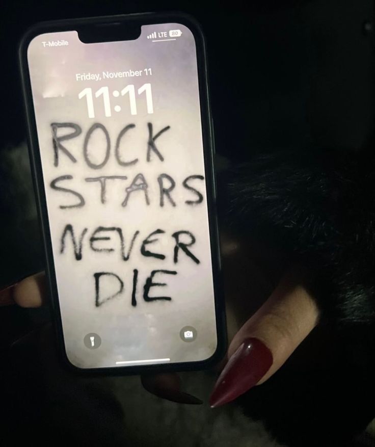 someone holding up a cell phone with the words rock stars never die written on it