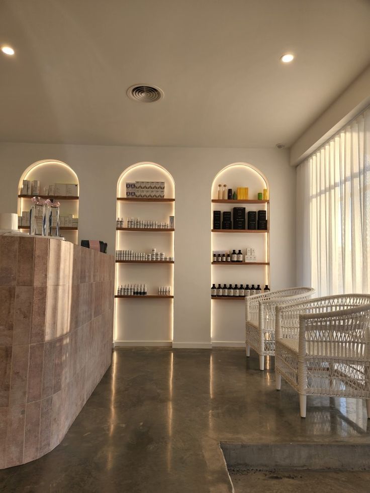 the inside of a store with several shelves and white chairs in front of them on concrete flooring