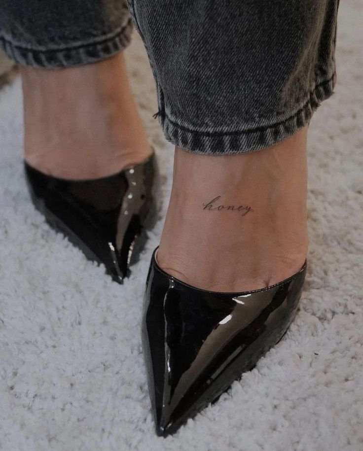 a woman's foot with a small tattoo on her left ankle and black shoes