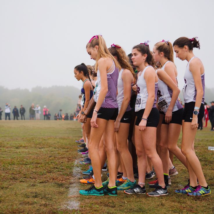 a group of young women standing next to each other on top of a field