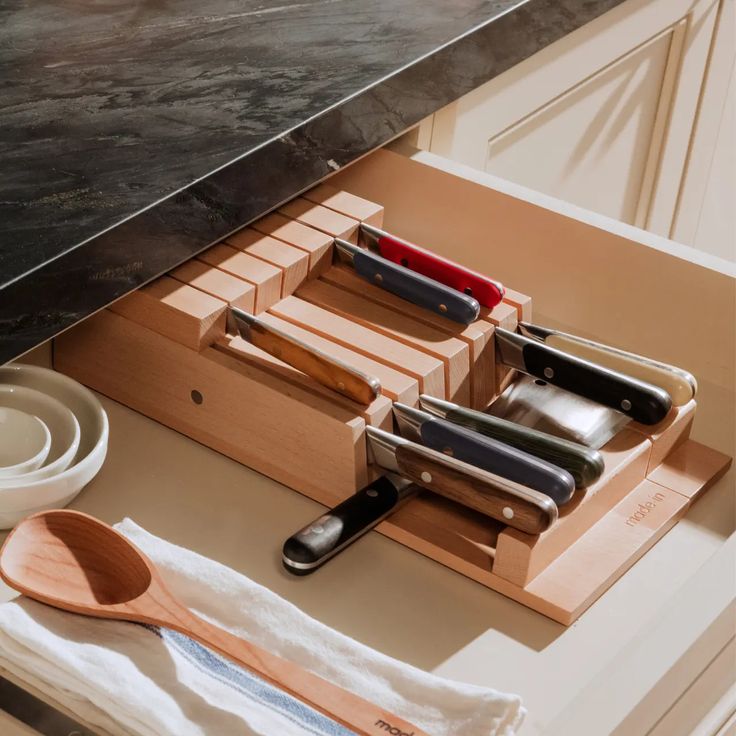 a kitchen drawer with utensils, knives and spoons in it on the counter