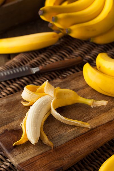 a bunch of bananas sitting on top of a wooden cutting board next to a knife