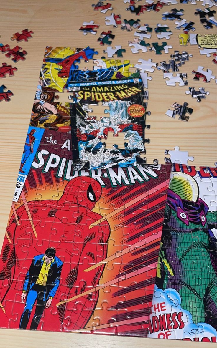 a wooden table topped with puzzle pieces covered in comic book covers on top of it