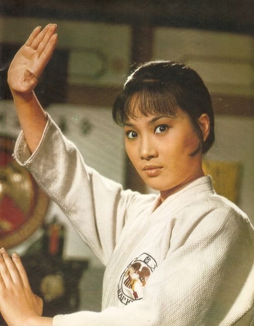 a woman in karate attire holding her hand up