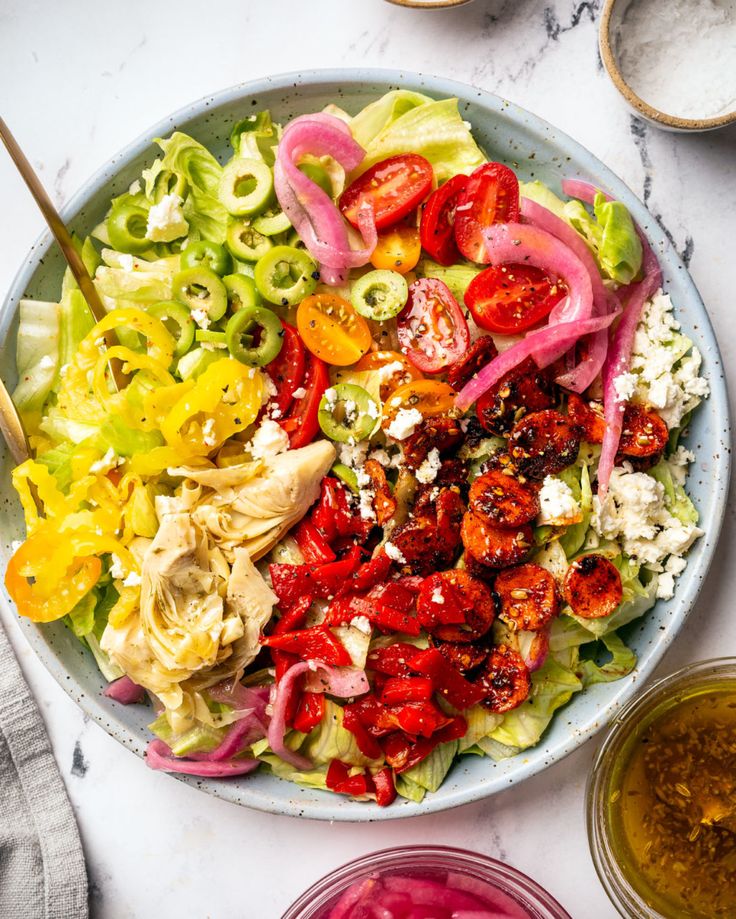 a salad with tomatoes, onions and lettuce in a bowl on a marble table