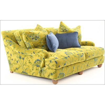 a yellow couch with blue pillows on it's arms and back cushions, sitting in front of a white background