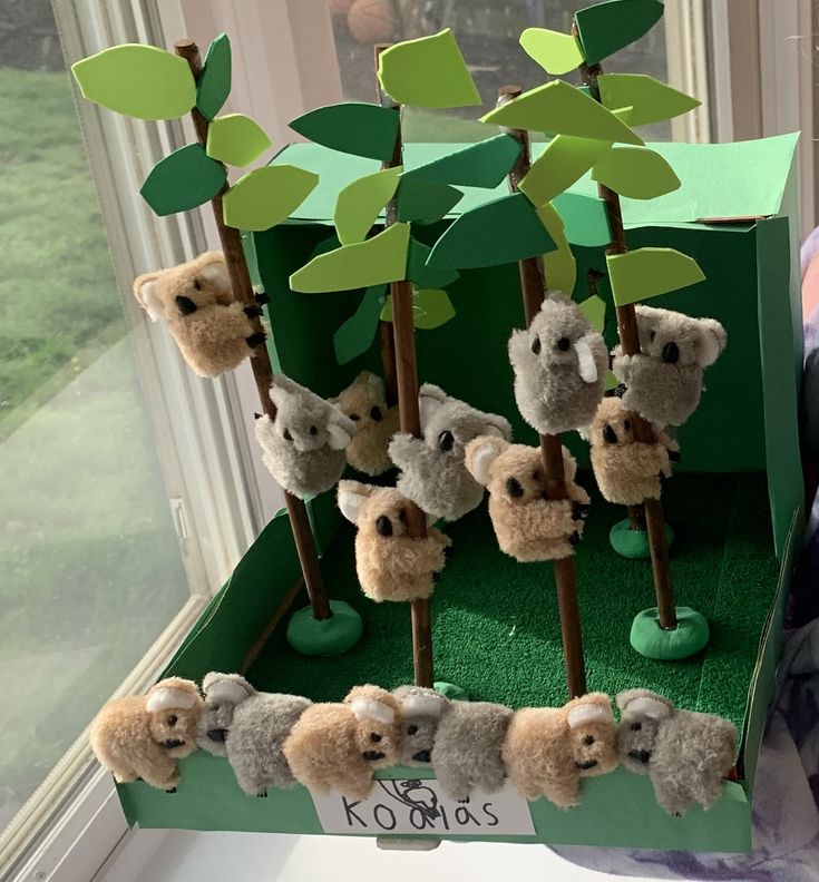 there are many stuffed animals on display in the window sill with green paper trees