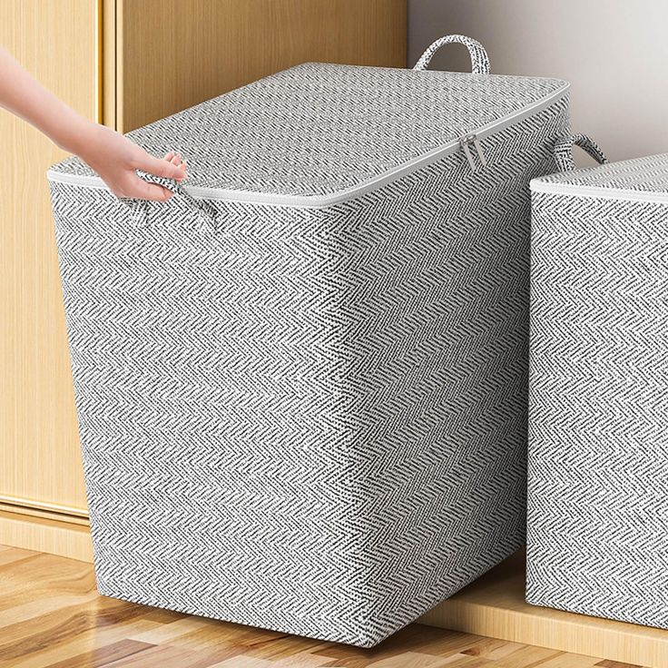 two white baskets sitting next to each other on a wooden floor