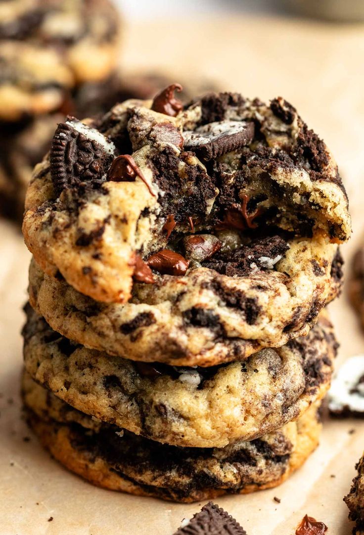 chocolate chip cookies stacked on top of each other with oreos scattered around them and one cookie in the middle