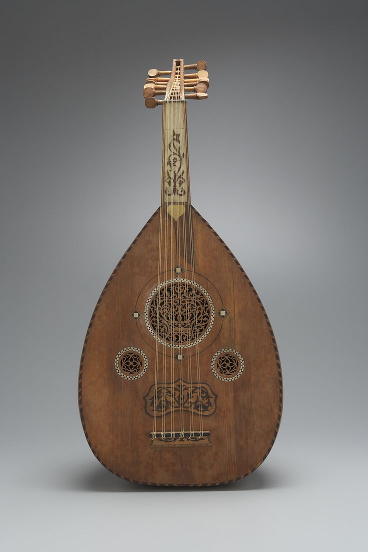 an old wooden instrument with intricate designs on it's body and neck, sitting against a gray background