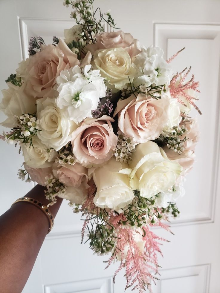 a person holding a bouquet of white and pink flowers