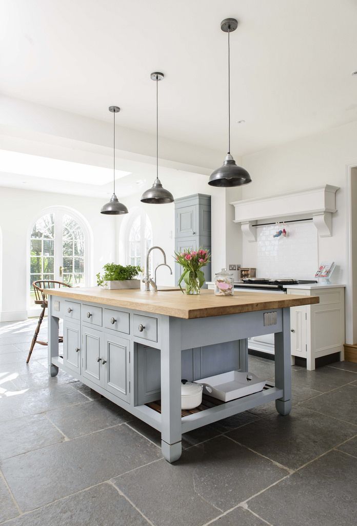 a large kitchen with an island in the middle and two lights hanging from the ceiling