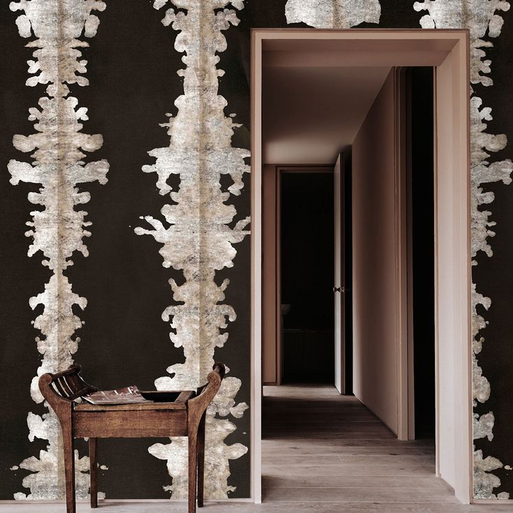 a chair sitting in front of a black wall with white paint on it and an open doorway leading to another room