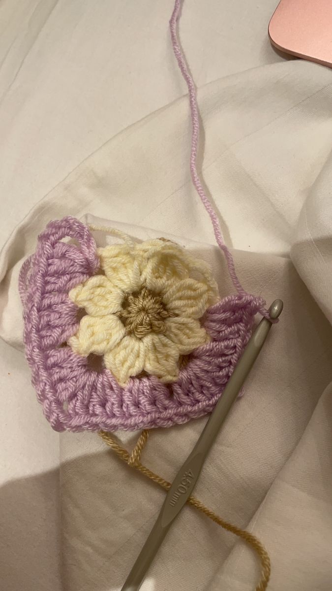 a crocheted flower sits on top of a white blanket next to a pair of scissors